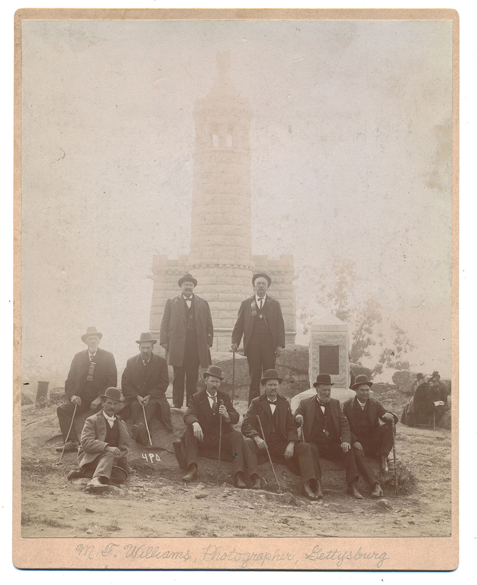 PHOTOGRAPH OF 8 VETERANS WITH BATTLEFIELD GUIDE ON LITTLE ROUND TOP