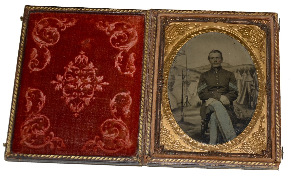 QUARTER PLATE TINTYPE OF AN INFANTRY CORPORAL WITH CAMP SCENE PAINTED BACKDROP